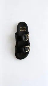 Sandalias de horma anatómica color negro, con dos tiras anchas en el empeine provistas de hebillas metálicas doradas.
