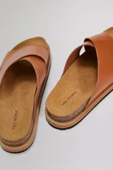 Sandalias planas modelo Santa Fe con tiras cruzadas de cuero negro, plantilla anatómica de corcho y suela de goma.