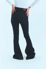 Pantalón de jean azul de tiro medio alto, corte oxford con botamanga ancha y tajo lateral. Cierre frontal con cinco botones metálicos.