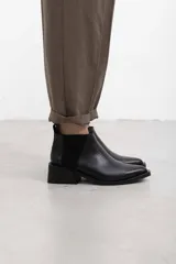 Botineta de cuero negro con textura sutil, con elásticos laterales y taco cuadrado bajo.