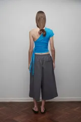 Bermuda gris de corte ancho, con pretina elástica, tiro bajo, bolsillos laterales y cierre lateral.