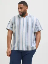Camisa de manga corta con cuello resort y ajuste relajado. Presenta un diseño de rayas verticales en tonos azules y blancos, con cierre frontal de botones. Confeccionada en una mezcla de algodón y lino, ofrece una textura ligera y fresca.