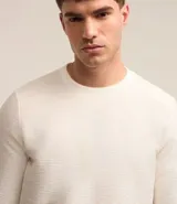 Remera de manga larga con cuello redondo y textura acanalada, confeccionada en una mezcla de poliéster y algodón.