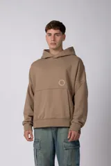 Buzo canguro oversize de frisa de algodón premium, color tostado, con capucha, recortes frontales y logo circular estampado en el pecho.