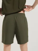 Bermuda deportiva de corte recto y largo medio, confeccionada en tejido técnico ligero de color verde oliva. Cuenta con cintura elástica y bolsillos laterales.