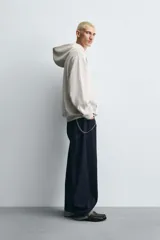 Sudadera tipo hoodie de color blanco hueso, con capucha, manga larga y bolsillo canguro frontal. Presenta un calce relajado y tejido de algodón con interior afelpado.