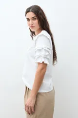 Remera de algodón color terracota con cuello redondo y mangas cortas con detalle de volados escalonados y costuras decorativas.