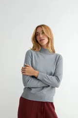 Polera de punto color beige, con cuello alto y mangas largas, de diseño básico y ajuste clásico.