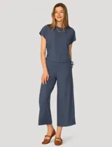 Conjunto de dos piezas compuesto por una remera de manga corta con cuello redondo y frunces laterales ajustables, y un pantalón de corte ancho con cintura elástica y bolsillos laterales.