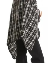 Ruana tejida con diseño de cuadros en blanco y negro, con borde ribeteado y cierre frontal tipo trenca con detalle de cuero sintético.