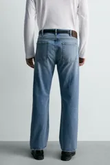Jeans de mezclilla rígida de algodón, color azul claro con efecto lavado y ligero desgaste. De tiro medio, corte recto desde la cadera hasta la rodilla y ligeramente acampanado en el bajo (bootcut). Cierre frontal con botonadura y cinco bolsillos.