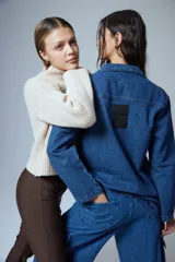 Pantalón tipo cargo de jean azul con corte oversize y tiro medio. Presenta múltiples bolsillos laterales y delanteros con solapa, confeccionado en algodón.