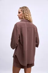 Camisa marrón de manga 3/4, con cuello clásico, botones frontales y un bolsillo en el pecho.