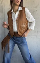 Chaleco de gamuza color camel con bordados en hilo crudo a lo largo de los bordes delanteros, diseño floral bordado en el lateral, tachas metálicas decorativas y botones a presión ocultos.