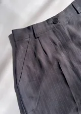 Pantalón sastrero gris a rayas verticales, de tiro alto con bolsillos y pretina trasera elastizada.