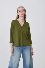 Remera de poliéster color verde oliva, con mangas 3/4, cuello en V con detalle de pliegue central y corte holgado.