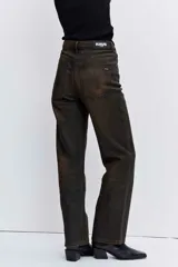 Pantalón de jean estilo wide leg con acabado engomado en tono marrón oscuro. Presenta un corte recto y holgado, con tiro medio y cierre frontal.