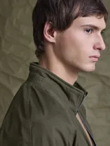 Campera tipo bomber color marrón, confeccionada en tela encerada, con cierre frontal, cuello tipo mao y puños y ruedo acanalados.