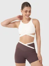 Top deportivo blanco con escote redondo y bandas elásticas cruzadas bajo el busto, con abertura en la espalda.