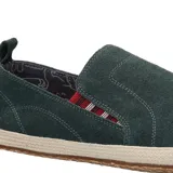 Alpargata de gamuza color verde oscuro, con detalle de elástico lateral a rayas rojas y blancas. Presenta una suela con borde de yute trenzado y base de goma.