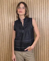 Musculosa negra sin mangas, con escote en V y cuello mao. Cuenta con detalles de alforzas y pespuntes blancos a contratono en la parte delantera.