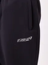 Pantalón tipo babucha de algodón y poliéster en color marrón, con cintura elástica, bolsillos laterales y logo de la marca bordado en la pierna izquierda.