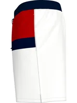 Short de baño Tommy Hilfiger con diseño de bloques de color blanco, azul marino y rojo. Cintura elástica con cordón ajustable y logo de la marca en la parte inferior.