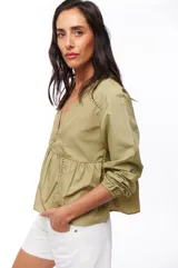 Blusa color verde oliva con escote en V, mangas largas abullonadas con puños elásticos y detalle de calado en hombros y cintura.