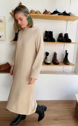 Vestido midi color beige de tejido acanalado, con cuello alto y mangas largas.