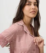 Pijama de dos piezas confeccionado en microfibra color rosado, con estampado geométrico. Incluye camisa de manga corta con cuello con solapa, cierre frontal con botones y detalles de encaje en las mangas, y short con cintura elástica.