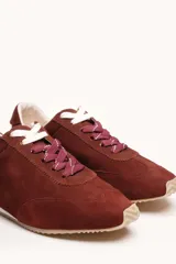 Zapatilla de gamuza color bordó con cordones bicolores, interior de cuero vacuno y suela de caucho blanca y beige.