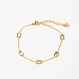 Pulsera de cadena fina en tono dorado con cinco dijes rectangulares engarzados que contienen cristales transparentes. Incluye cierre de mosquetón y cadena de alargue con terminal circular.