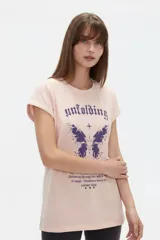 Remera de algodón color rosado, de corte holgado y manga corta con vueltas. Cuenta con estampado frontal en tonos violetas que incluye una mariposa y texto estilo gótico.