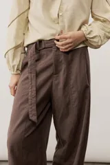 Pantalón de corte ancho, color marrón, con pretina alta y cinturón de la misma tela con hebilla rectangular.