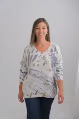 Sweter de punto con corte amplio, escote en V y mangas largas. Presenta un diseño estampado abstracto sobre una base color crudo con detalles en tono dorado.