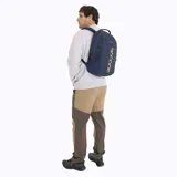 Mochila Merrell de 25 litros, color azul marino, con diseño funcional y resistente. Presenta una tira central decorativa en tono beige, compartimento principal con cierre y correas ajustables.