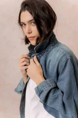 Camisa de denim de lavado medio con calce oversize, cuello camisero, cierre frontal con botones y bolsillos aplicados en el frente.