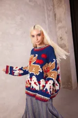 Sweater de lana tejido y bordado a mano, de calce holgado con cuello redondo y puños. Presenta un diseño artesanal con motivos figurativos en colores azul, beige, blanco y rojo.