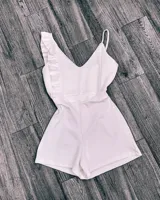 Mono corto blanco con escote en V, breteles finos y un volado en el hombro izquierdo.