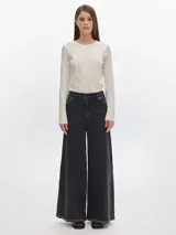 Pantalón de jean negro de tiro alto, corte wide leg y ruedo con costura a la vista.