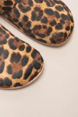 Zueco destalonado de cuero vacuno con estampado de leopardo. Presenta una tira ancha con hebilla metálica dorada sobre el empeine.