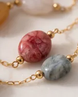 Pulsera de cadena fina con baño de oro, adornada con piedras naturales en tonos rosado y gris.