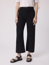 Pantalón jean color beige, de tiro alto y pierna ancha con terminación desflecada.