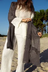 Chal rectangular de lino en color gris oscuro, con terminaciones de volados en los extremos. Tejido ligero y fresco, ideal para usar como accesorio versátil.