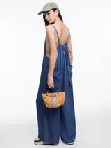 Enterito de denim suave confeccionado en 100% lyocell, con escote recto y breteles finos regulables que se ajustan en la espalda. Presenta una silueta amplia de pierna recta, caída fluida, bolsillos traseros aplicados y costuras a contratono.