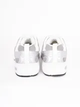 Zapatillas deportivas de estilo urbano, color blanco con detalles en plateado, confeccionadas en malla y material sintético, con suela de goma.