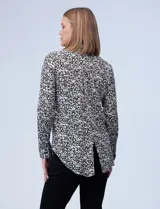 Camisa estampada blanca y negra con cuello clásico, abertura frontal con botones ocultos y mangas largas con puños abotonados.