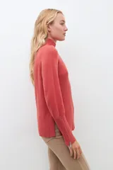 Polera de punto color ladrillo, de cuello alto y mangas largas con cierre en los puños.