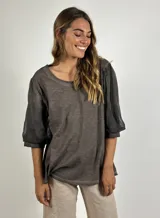 Blusa gris de manga corta con mangas abullonadas de tela transparente y cuello redondo.
