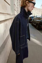 Cazadora de denim azul oscuro con cuello solapa, manga larga, cierre frontal con botones metálicos y bolsillos delanteros de plastrón.